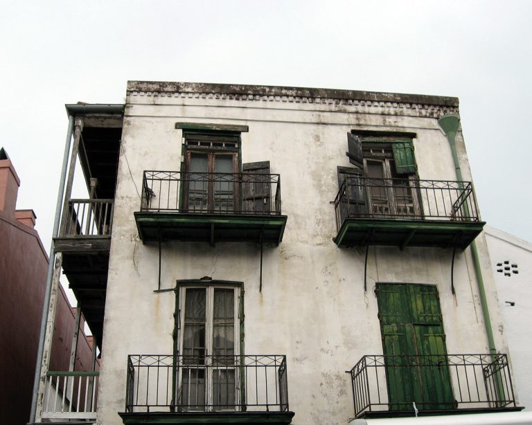 Weathered exterior of a very old white home in new orleans