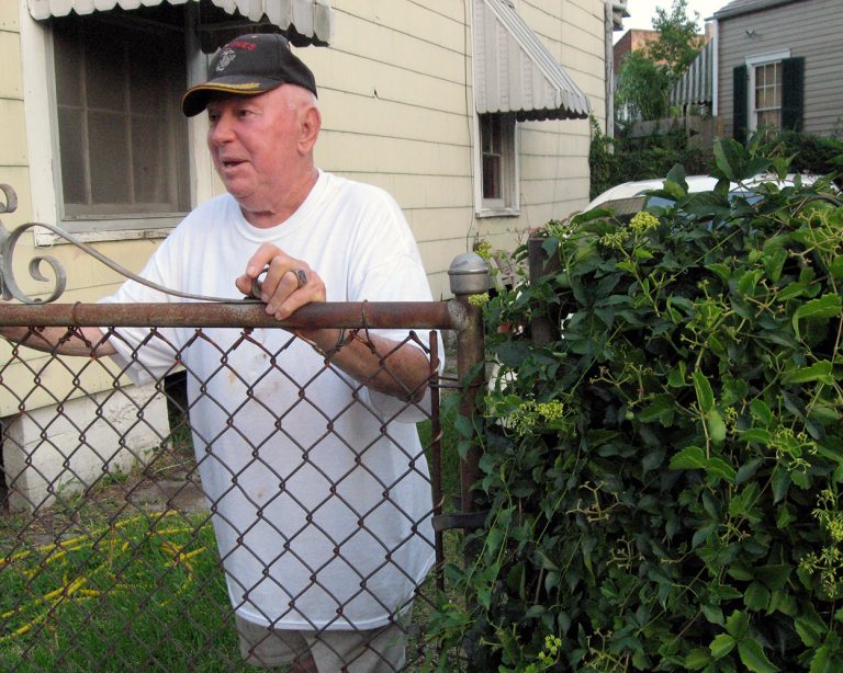 an old man talking over a wire fence in new orleans